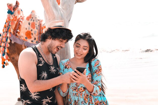 young happy couple front pose using celphone at beach indian pakistani model