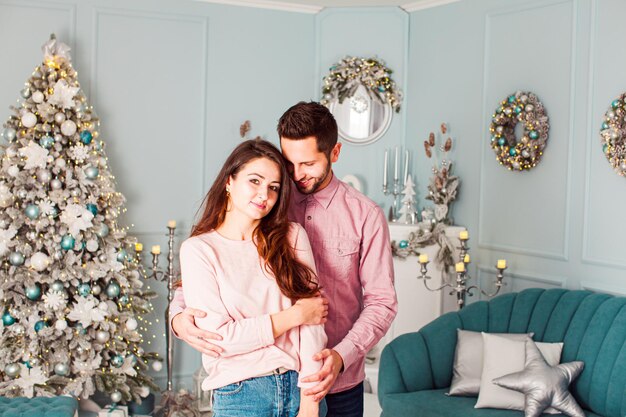 Young happy couple have fun and huggingnear christmas tree