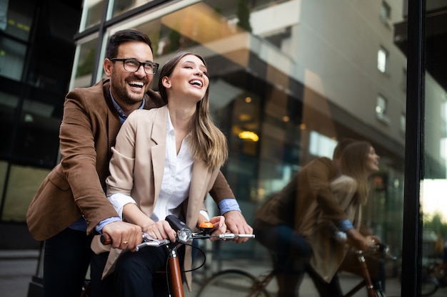 街で楽しんで自転車に乗る若い幸せなカップル