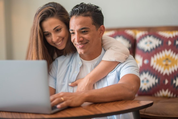 Young happy couple at home boy and girl surfing the web\
together smiling and enjoying internet search connection modern\
people in indoor home leisure activity using laptop relationship\
and happiness