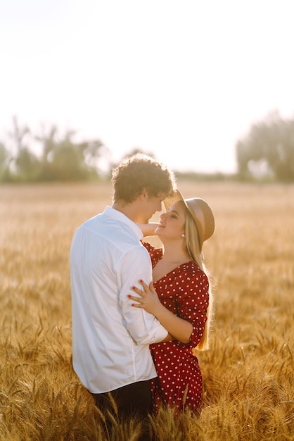 Young happy couple hugging on a wheat field on the sunset Enjoying time together