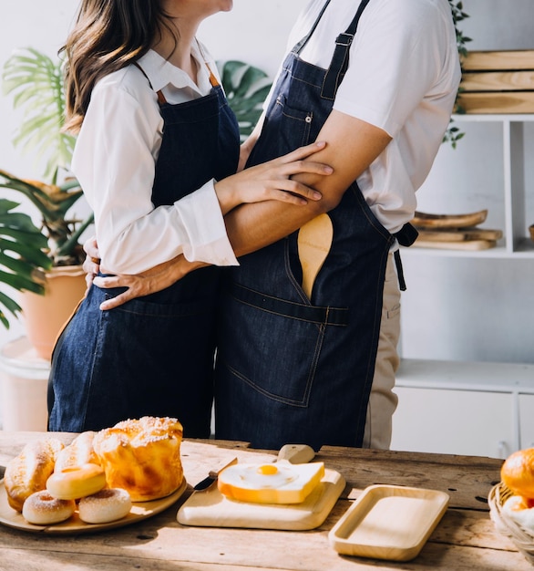 Young happy couple is enjoying and preparing healthy meal in their kitchen and reading recipes on the laptop