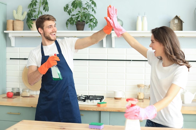 Young happy couple is having fun while doing cleaning at home.