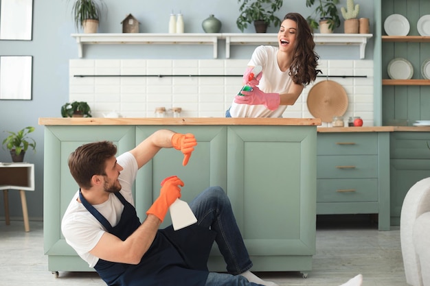 若い幸せなカップルは家で掃除をしながら楽しんでいます。