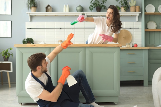 Young happy couple is having fun while doing cleaning at home.