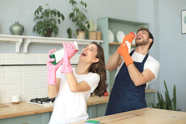 Young happy couple is having fun while doing cleaning at home.