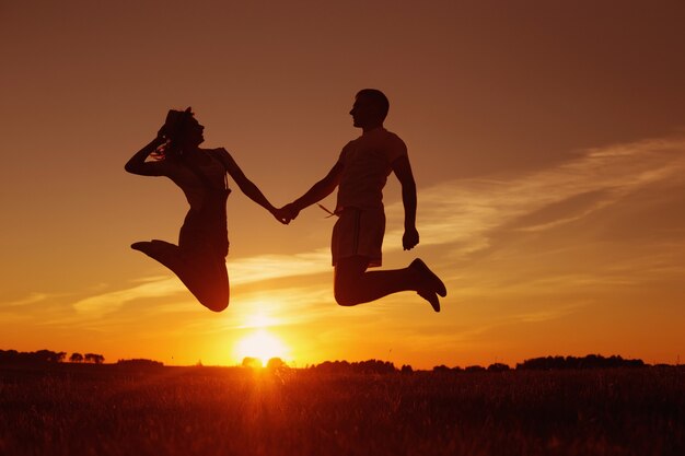 Young happy couple jumping  on sunset