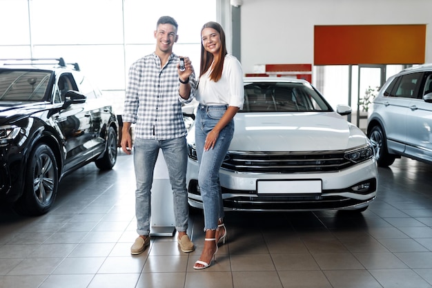 Young happy couple just bought a new car in a dealership