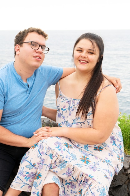 Young happy couple in love embracing while dating on seaside on summer day, man and woman smiling enjoying intimate moment outdoors