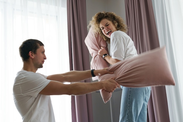 Young and happy couple during the pillow fight in their apartment