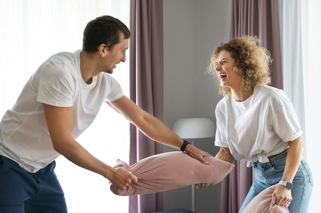 Young and happy couple during pillow fight in their modern apartment