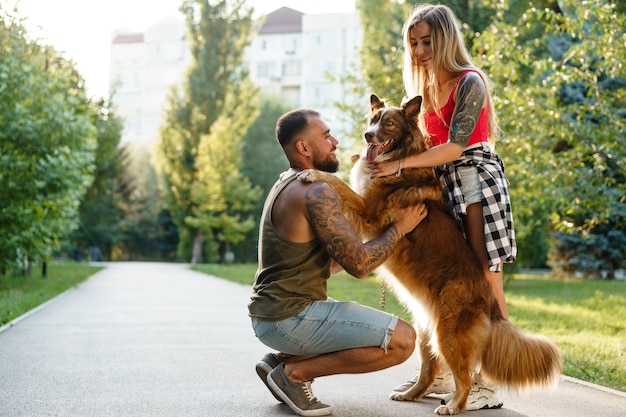 Giovane coppia felice che gioca con il loro cane sorridente nel parco