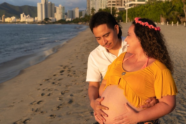 Young happy couple pregnant woman on beach