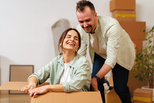 Photo young happy couple in room with moving boxes at new home