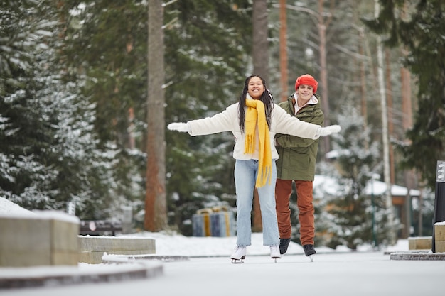 야외에서 함께 스케이트와 겨울 휴가를 즐기는 젊은 행복한 커플