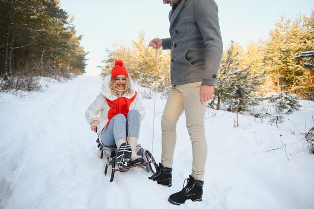 Young happy couple sledding in winter at forest