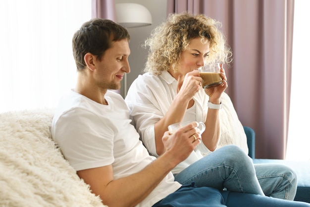 Young happy couple spending time together and drinking coffee at home