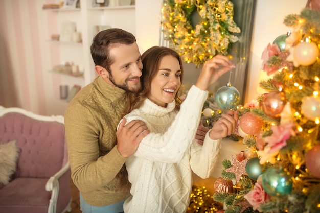 Young happy couple standing near Christmas tree