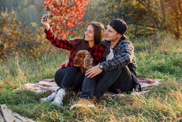 Young happy couple taking selfie using smartphone in the park.