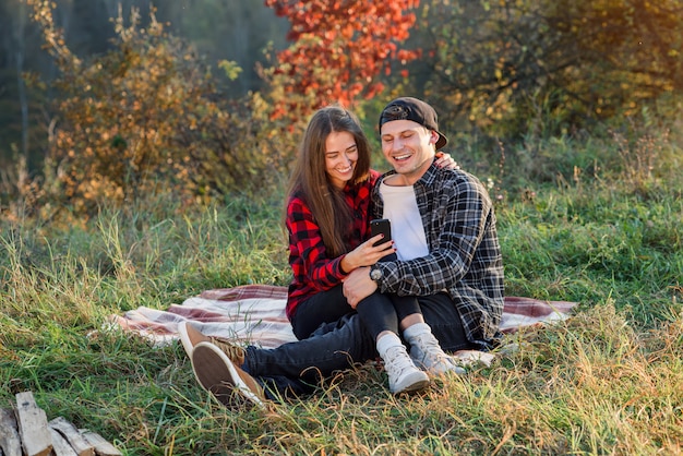 Young happy couple taking selfie using smartphone in the park.