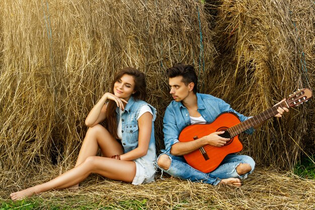 Young happy couple in the village among the haystacks.