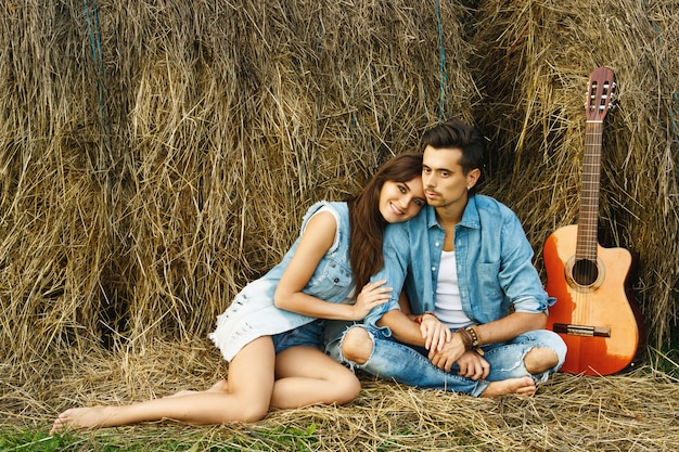 Young happy couple in the village among the haystacks.