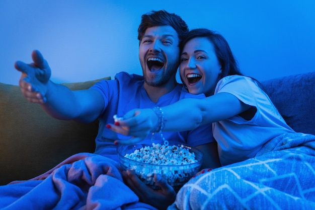 Young and happy couple watching comedy TV show at home
