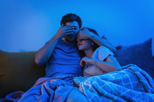 Young and happy couple watching horror movie at home