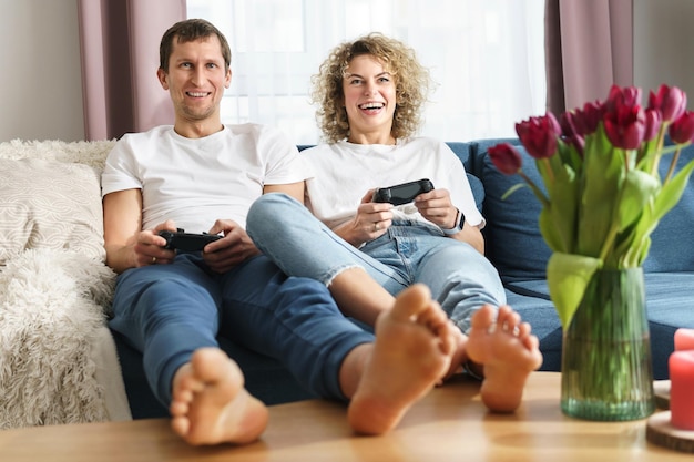 Young happy couple with a gamepads are playing video game console