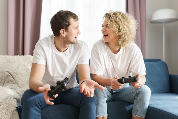 Young happy couple with a gamepads are playing video game
console