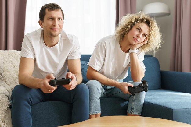 Young happy couple with a gamepads are playing video game\
console