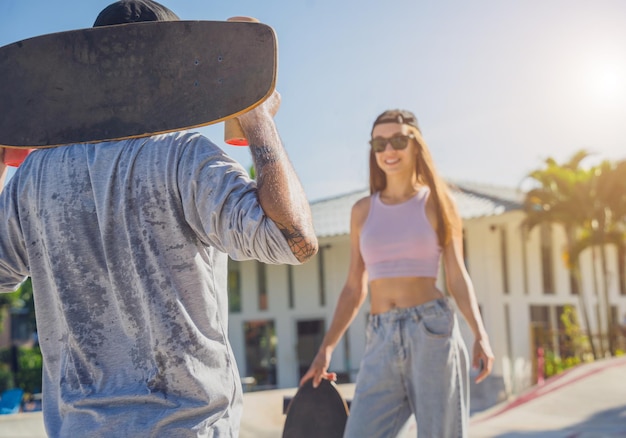 Young happy couple with skateboards enjoy longboarding at the skatepark