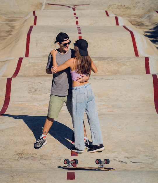 스케이트 보드 를 들고 있는 행복 한 젊은 부부 는 스케이트 파크 에서 롱보드 를 즐긴다