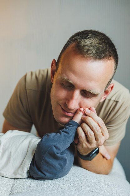 Young happy dad kisses his little sons feet Happy father