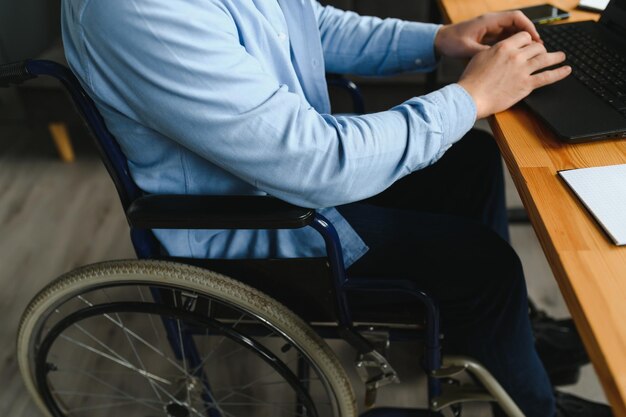 Photo young happy entrepreneur in wheelchair working on laptop at home