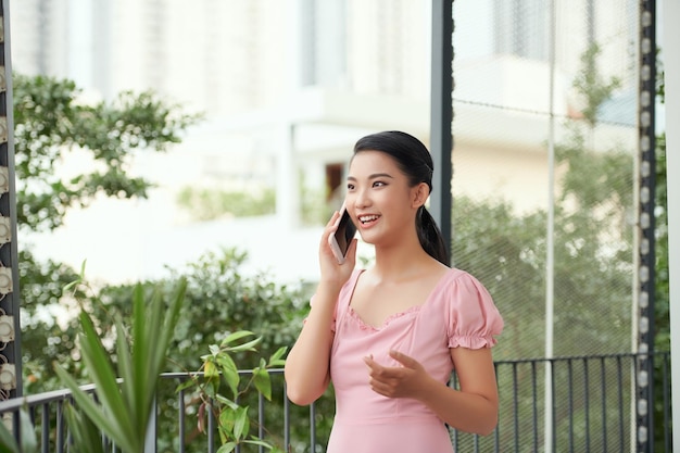 屋外で分離された携帯電話で話している若い幸せな興奮して笑っている女性