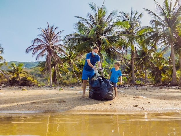 Young happy family activists collecting plastic waste on beach Dad and son volunteers clean up garbage Environmental pollution problems Outdoor lifestyle recreation Natural education of children