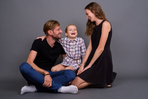 Young happy family bonding together against gray wall