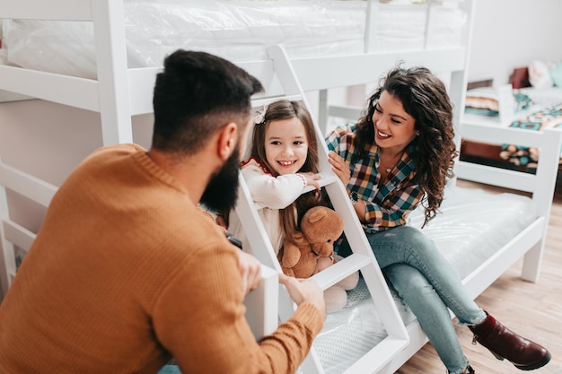 Young happy family buying new bed and mattress in big furniture store