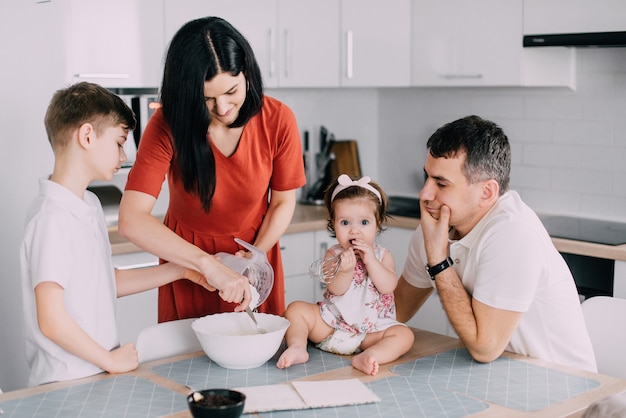 Foto giovane famiglia felice che cucina insieme la cena in cucina