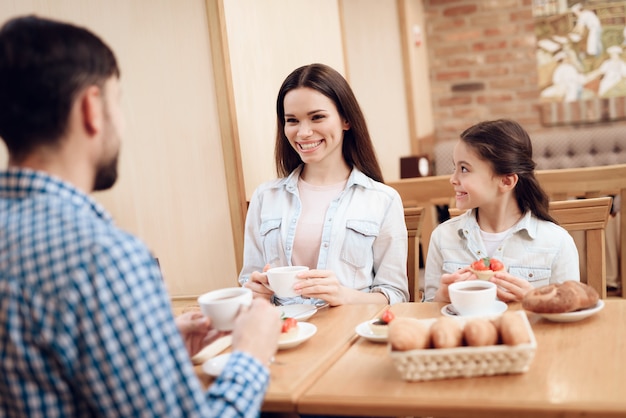 カフェテリアでケーキを食べる若い幸せな家族。