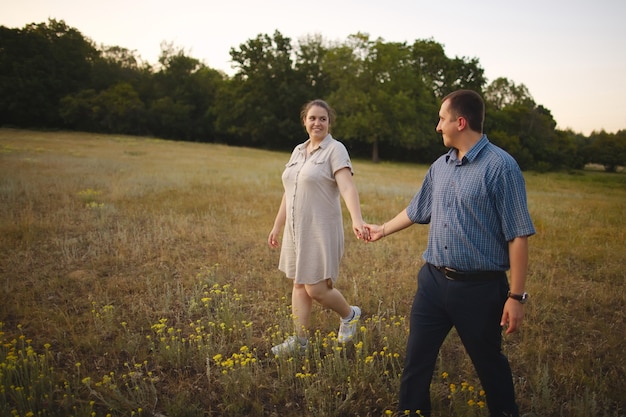 Young happy family holding hands walking in nature on the background of the forest