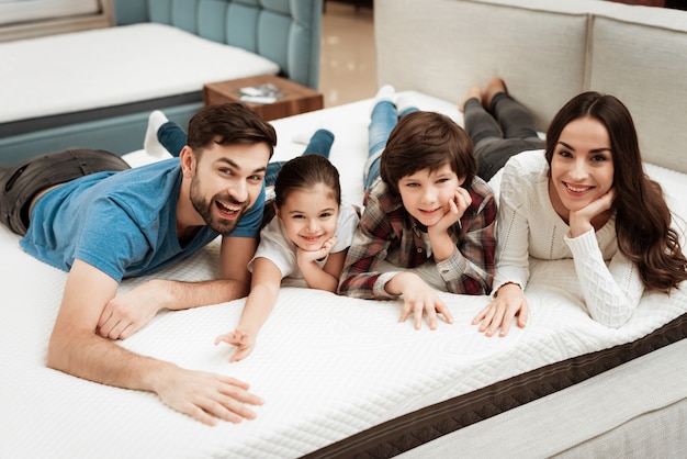 Young Happy Family Relaxing on Soft Bed in Store