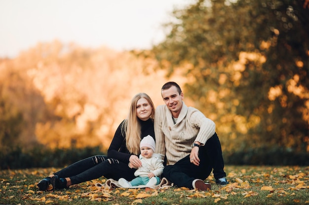 Giovane famiglia felice che sorride alla macchina fotografica e che sta insieme