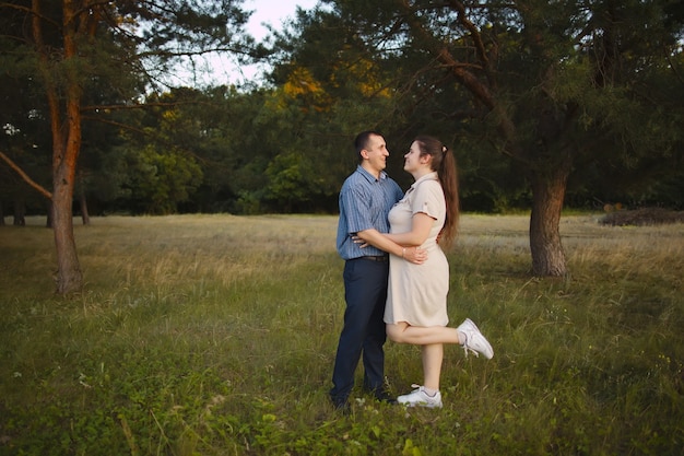 Young happy family stands in nature and hugs each other