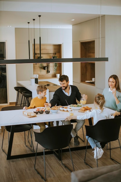 Фото Молодая счастливая семья разговаривает во время обеда за обеденным столом в квартире