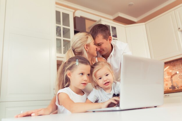 Photo young happy family using laptop while sitting at kitchen at home