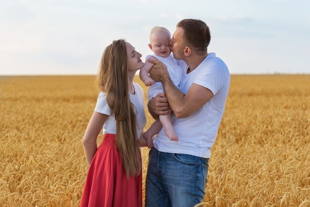 Young happy family walks on field.