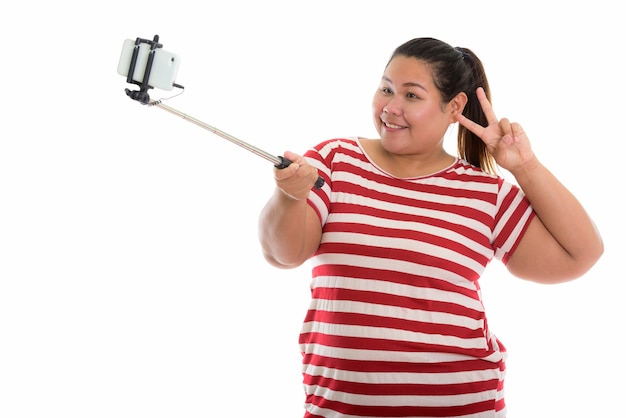 young happy fat Asian woman smiling and taking a selfie