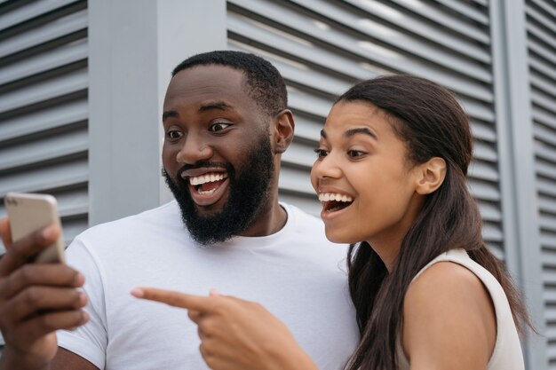 Young happy friends using mobile phone shopping online focus on African man face